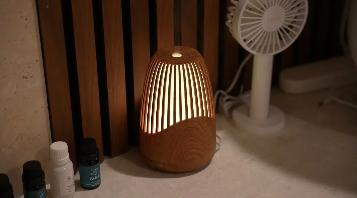 A warmly lit timber aroma diffuser and essential oils on a stone ledge at The Skin Doctor