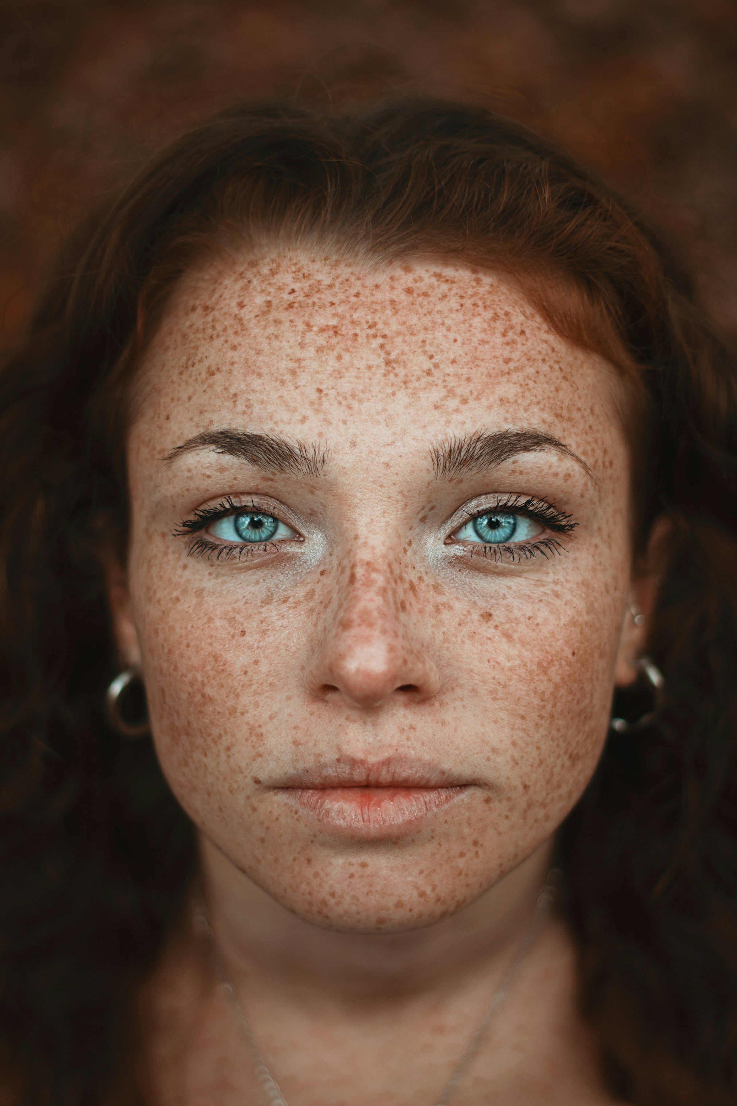 Close portrait of a woman with freckles and blue eyes — natural skin pigmentation and character.