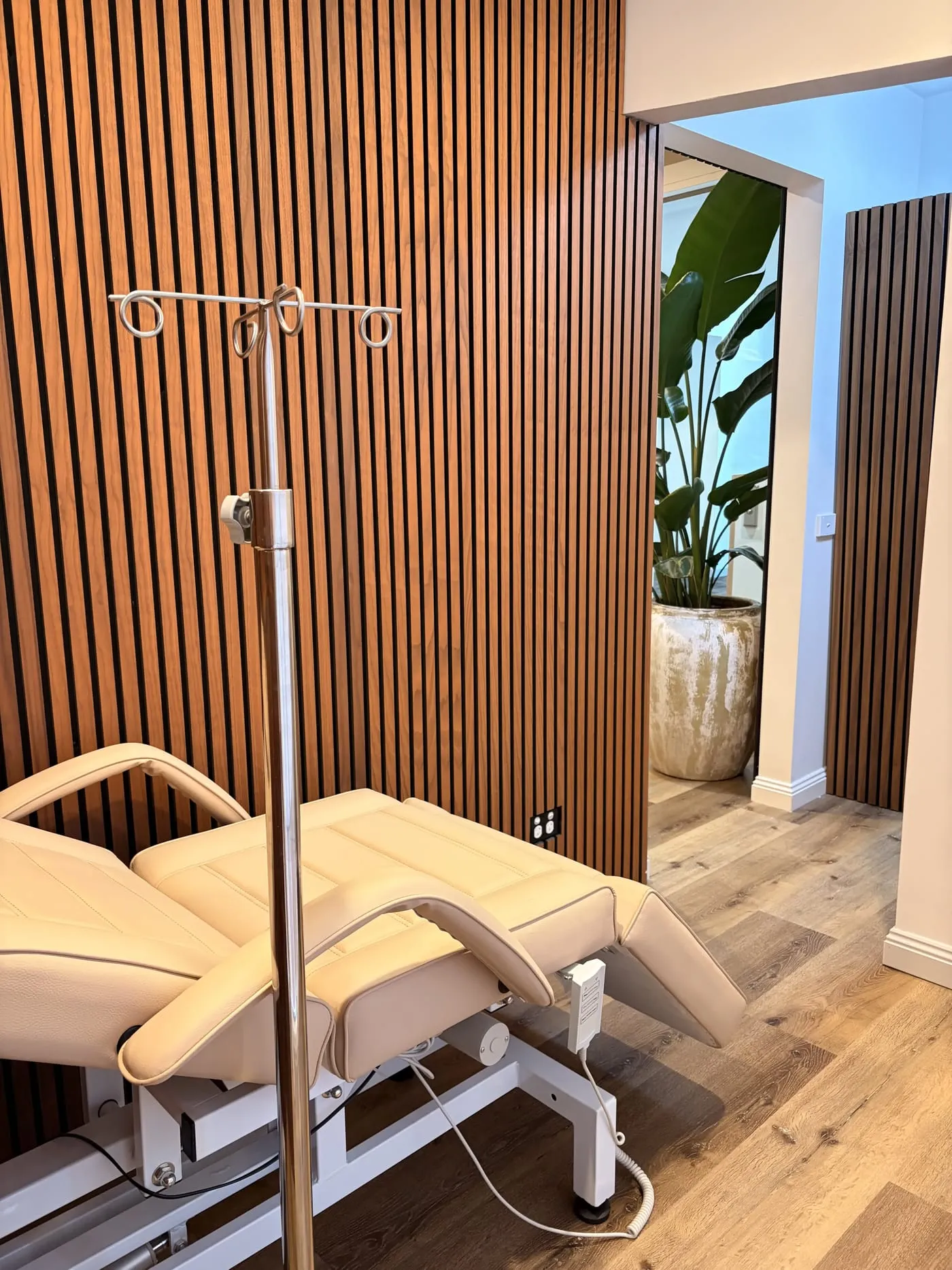 The IV infusion lounge at The Skin Doctor — a treatment recliner and IV stand against a warm timber-panelled wall