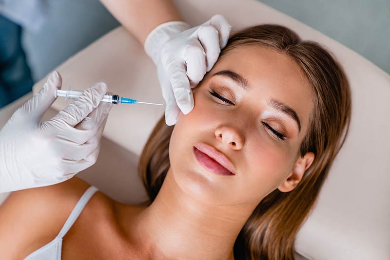 A cosmetic specialist administering cosmetic injectables to a woman during a cosmetic skin treatment with skin doctor